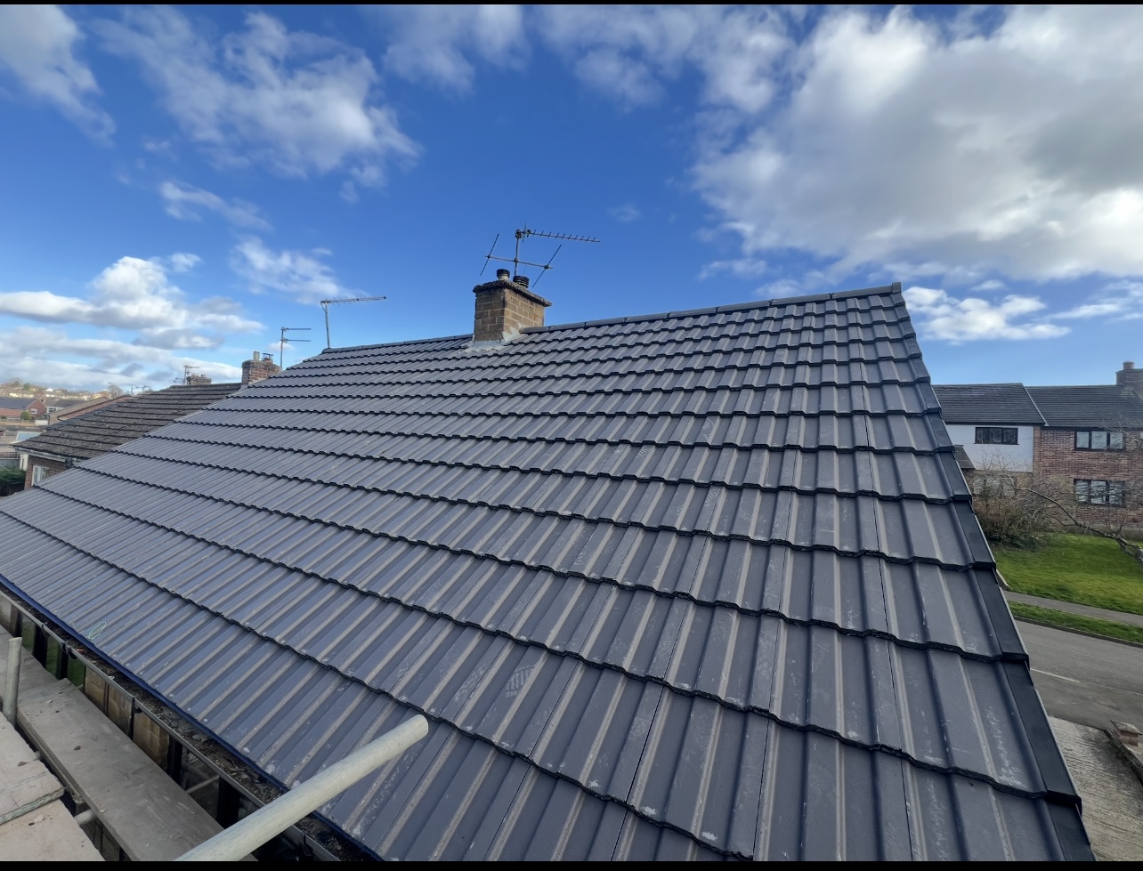 Completed dark tiled roof with a chimney, photographed by First Choice Roofing